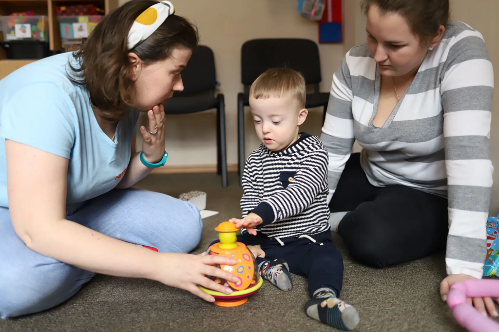 На фото двоє жінок грається з хлопчиком